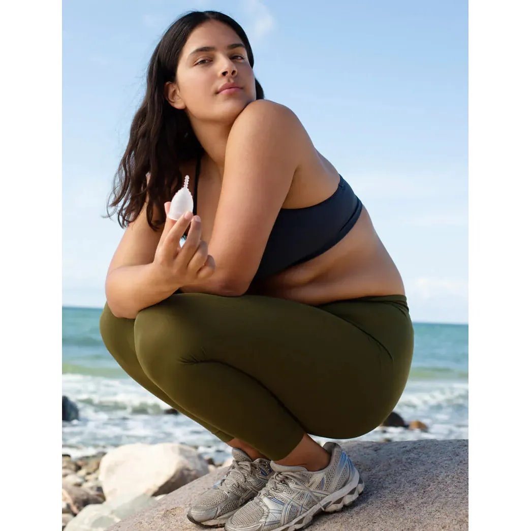 AllMatters Menstruatiecup (OrganiCup) in hand van model naast de zee