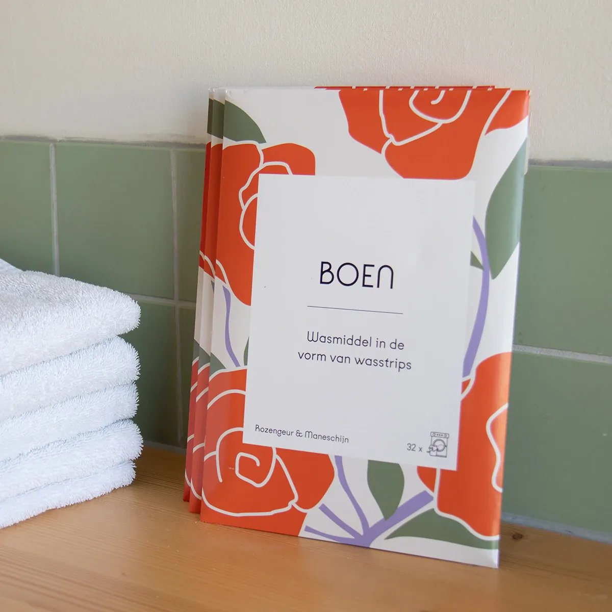 Boen Wasstrips Rozengeur & Maneschijn (32 stuks) pakjes naast handdoeken