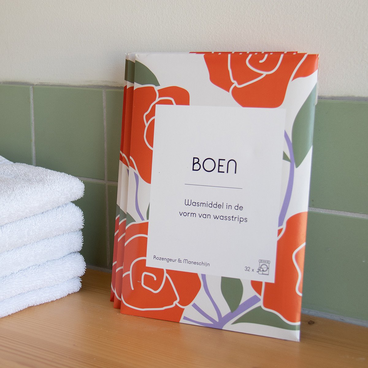 Boen Wasstrips Rozengeur & Maneschijn (32 stuks) pakjes naast handdoeken